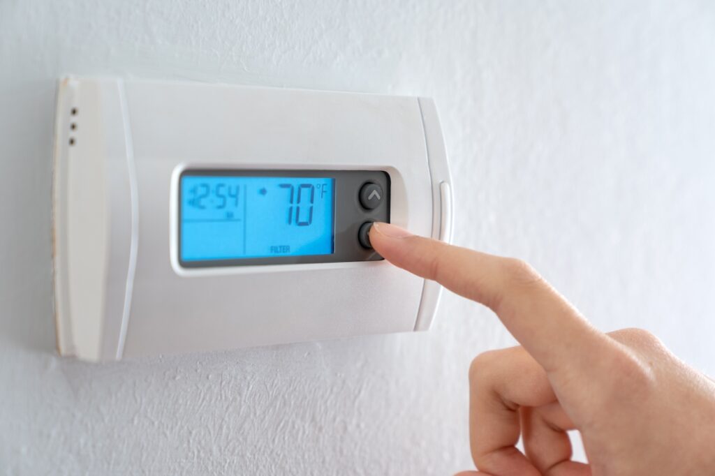 Person changing temperature on thermostat