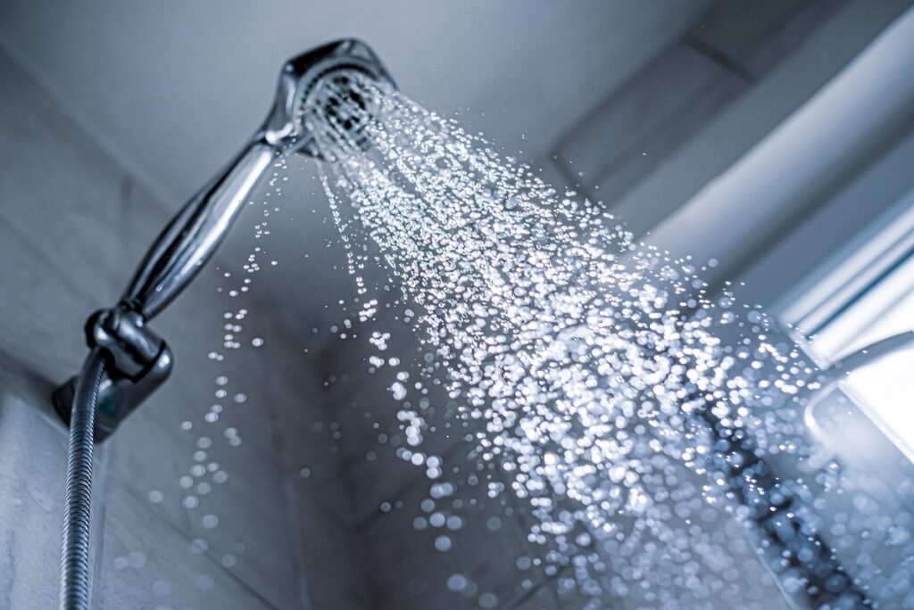 Water running from shower head and faucet in the bathroom, view from below.